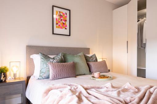 a bedroom with a bed with pillows and a cup of tea on it