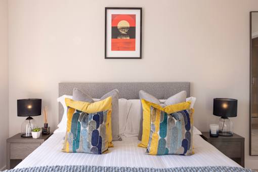a bed with yellow and blue pillows and a picture on the wall above it
