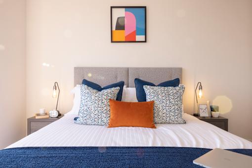 a bedroom with a bed with pillows and a laptop