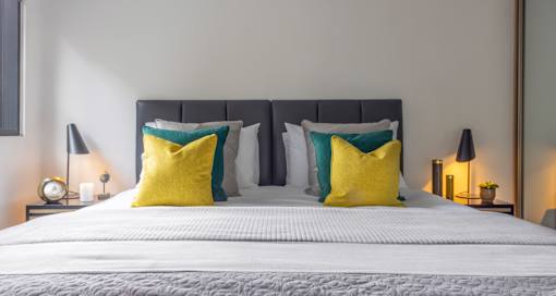 a bedroom with a bed with yellow pillows and white bedding