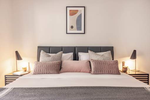 a bedroom with a bed with pillows and a painting on the wall