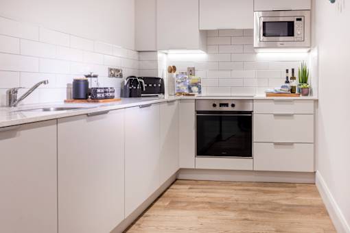 a white kitchen with a wooden floor and white cabinets