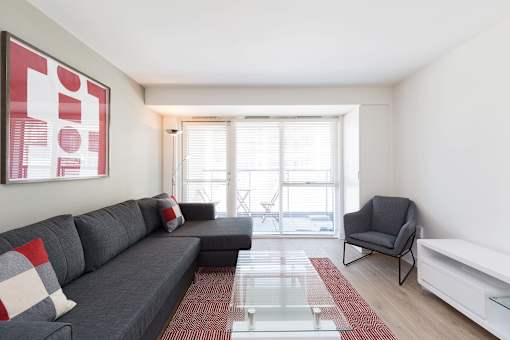 a living room with a gray couch and a glass table  and a large window
