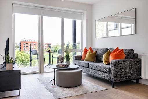 a living room with a gray couch and a round coffee table and sliding glass doors