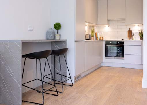 a kitchen with white cabinets and black bar stools