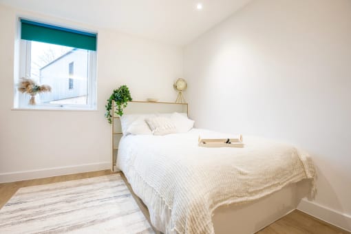 a white bedroom with a bed and a window