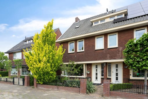 the front of a brick house with a yard and a fence