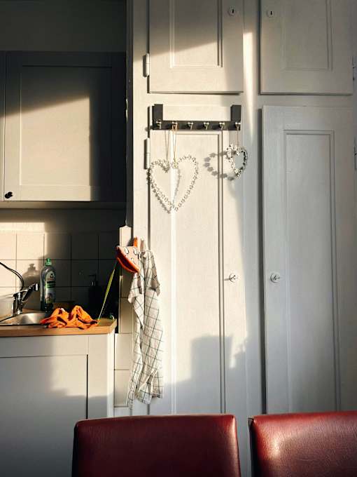 a small kitchen with a white refrigerator and a red chair