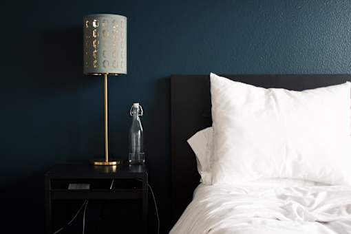 a bedroom with blue walls and a bed with a white pillow and a nightstand