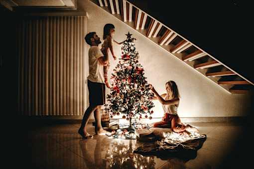 a family decorates a christmas tree in their living room