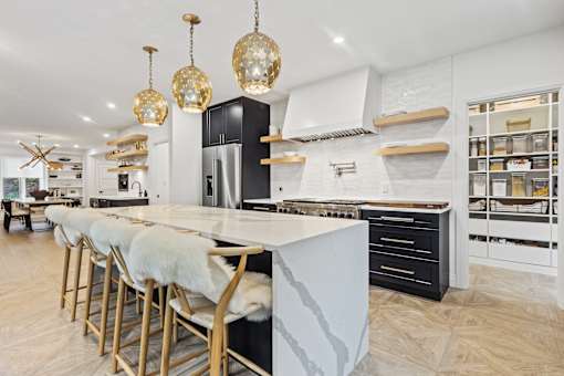 a large kitchen with a marble counter top and a long island with chairs