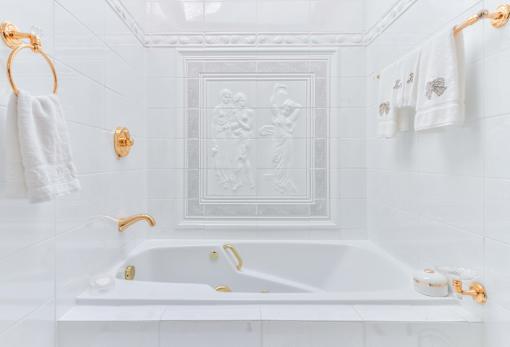 a white bathroom with a bath tub and white tiles