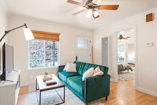 a living room with a green couch and a ceiling fan