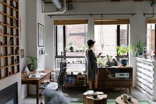 a woman standing in a living room looking out of a window