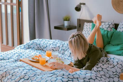 a woman laying in bed eating breakfast on her bed