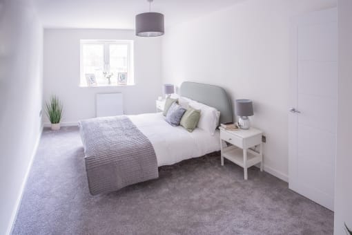 a white bedroom with a bed and a grey carpet