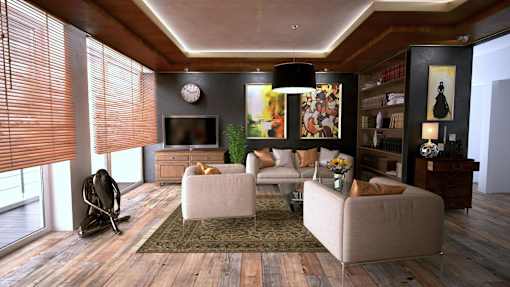 A living room with a grey sofa, a white armchair, a chair, a television, a clock, a potted plant, a rug, and a bookshelf.