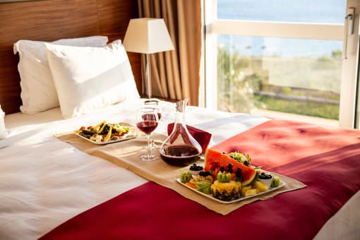 a bed with a tray of food and wine on it