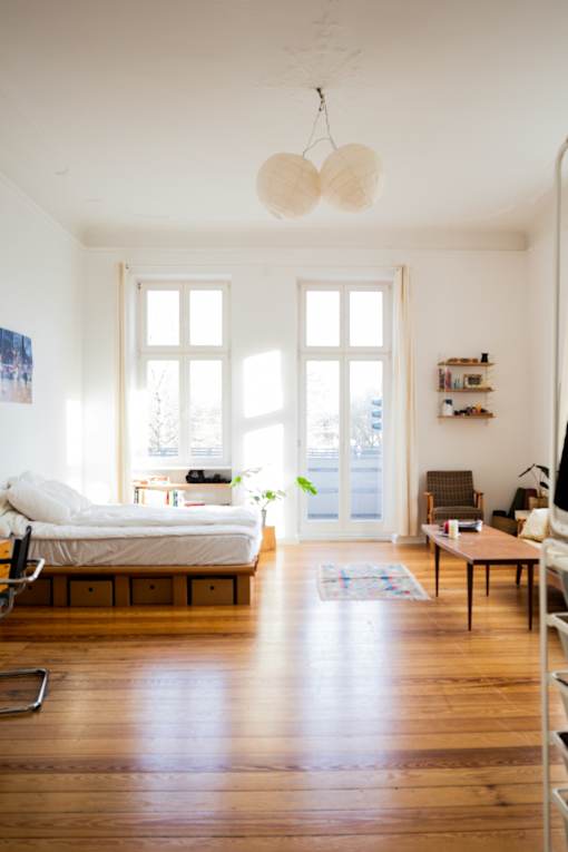 a bedroom with a bed and a living room with a wood floor
