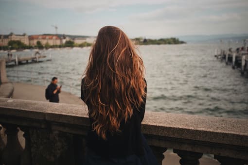 a woman sitting on a ledge by the water