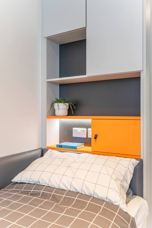 a small bedroom with a bed and a shelf above it