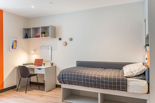 a small bedroom with a bed and a desk with a computer