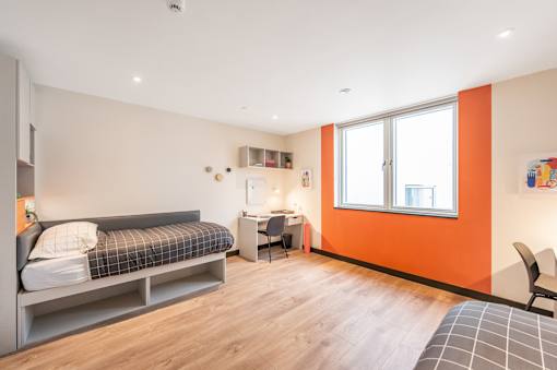 a bedroom with a bed and a desk and a window