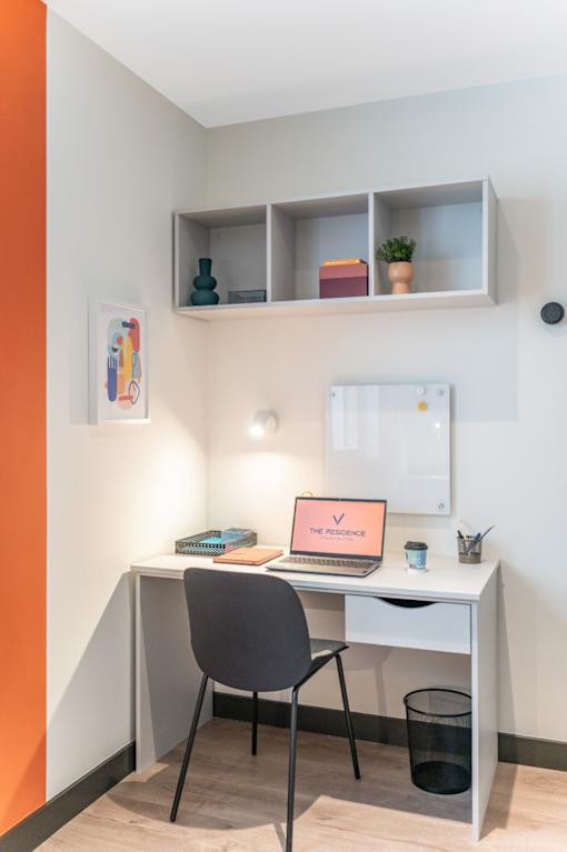a desk with a laptop and a chair in a room