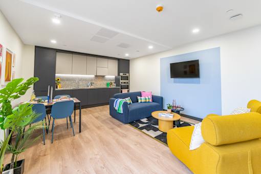 a living room and kitchen with yellow couches and a table and chairs