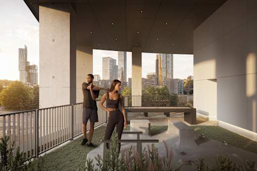 Two people standing on a balcony with a cityscape view.