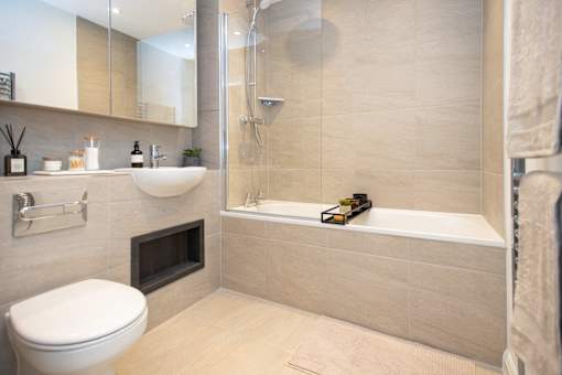 A modern bathroom with a white toilet, a sink, and a bathtub.