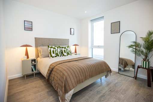 A bedroom with a bed, nightstand, and lamp.