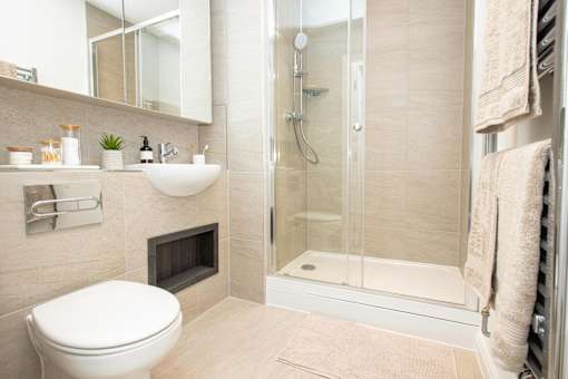 A bathroom with a toilet, sink, mirror, and shower.