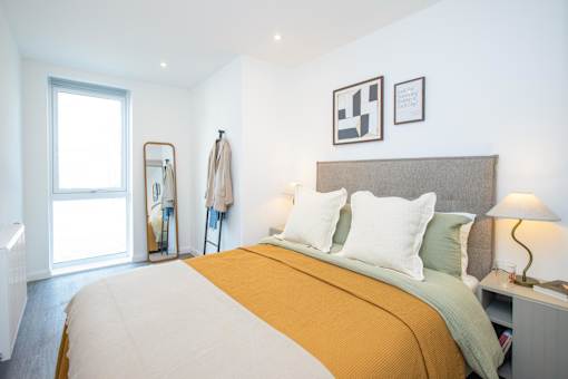 A bedroom with a bed, a nightstand, and a mirror.