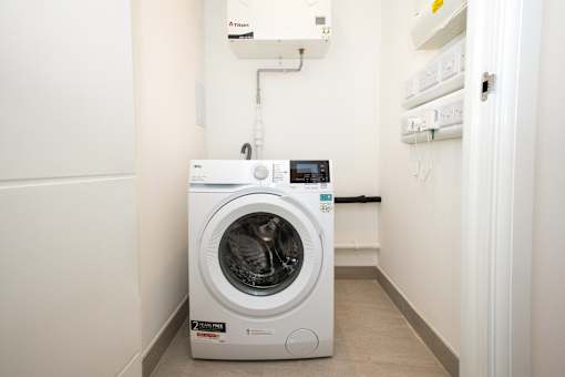 A white front loading washing machine with a digital display and a 2 year warranty sticker.