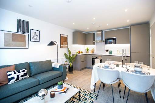 A modern living room with a grey sofa and a dining table set for two.