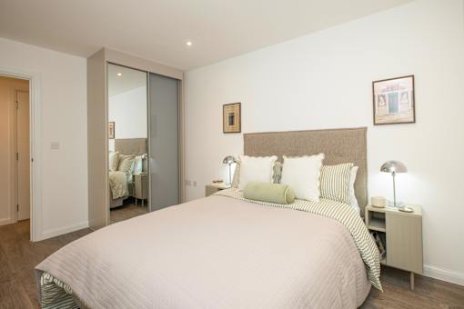 A bedroom with a large bed and a nightstand with a lamp.