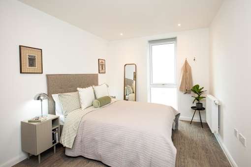 A bedroom with a large bed and a small table with a lamp.
