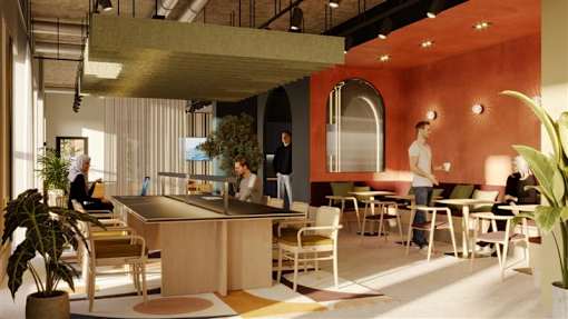 A modern office space with people working at desks and a reception area.