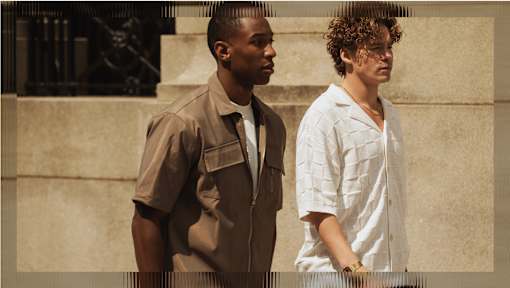 Two men standing next to each other in front of a building.