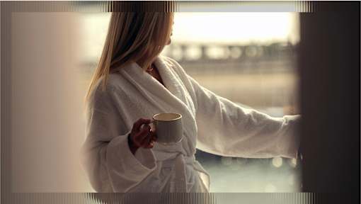 A woman in a white robe is holding a cup.