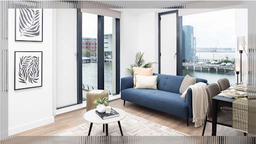 A living room with a blue couch, a coffee table, and a view of the city.