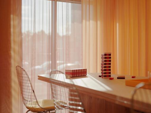 A chair is placed in front of a desk with a stack of books and a few other items on it.