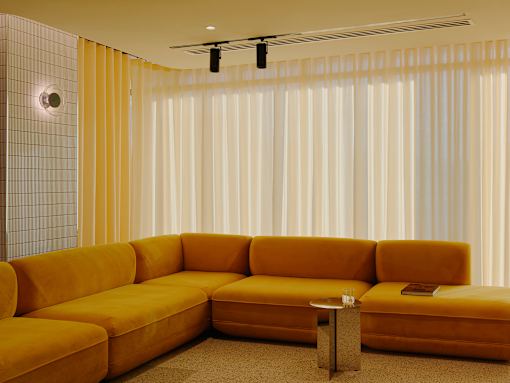 A yellow couch with a small table in front of it.