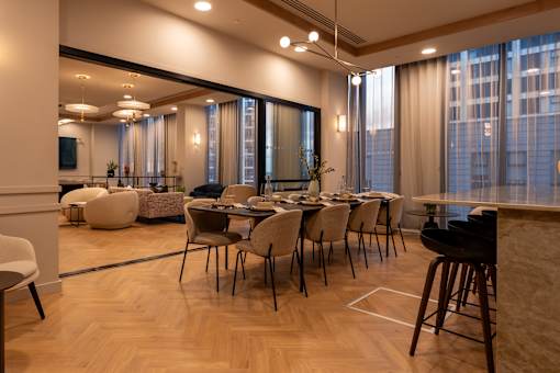 Modern dining set features beige upholstered chairs and a long dark wood table at Lighthaus Liverpool Apartments, Liverpool
