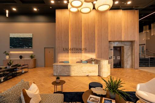 A modern living room with a wooden floor and a large wooden wall with the word "LIGHTHAUS" on it.