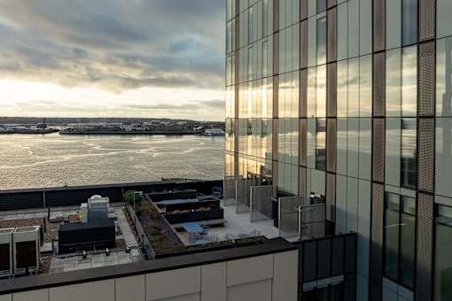 A modern building with a view of the water and a cloudy sky.