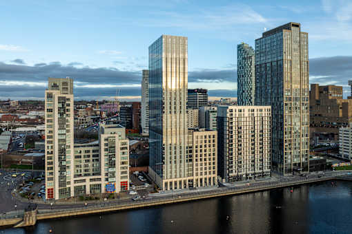 A cityscape with a river in the foreground and buildings of varying heights.