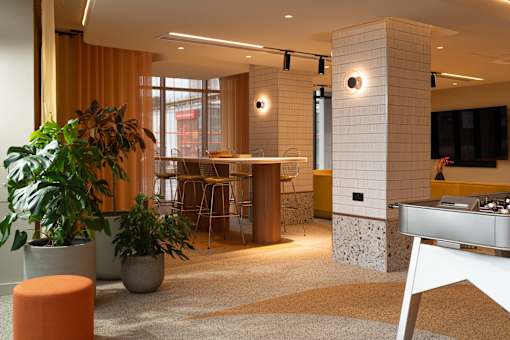 A modern office space with a large window, a desk, and a potted plant.
