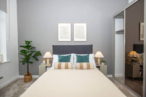 A bedroom with a large bed and two lamps.